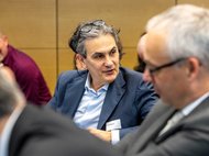 Personen in einem Meeting, teilweise verdeckt, formelle Kleidung.