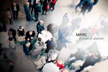 An aerial view of a professional networking event featuring numerous attendees in conversation around tables. The logo for MPIfG friends & alumni is prominently displayed, indicating the affiliation of the gathering.