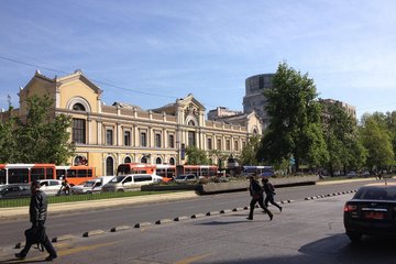 UCEN, Chile: Grand historic building featuring arched windows and detailed facade, with pedestrians crossing a busy street lined with vehicles and trees.