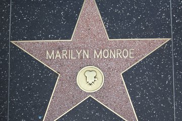 A pink terrazzo star on the Hollywood Walk of Fame honors Marilyn Monroe, with her name in gold lettering and a film camera symbol.